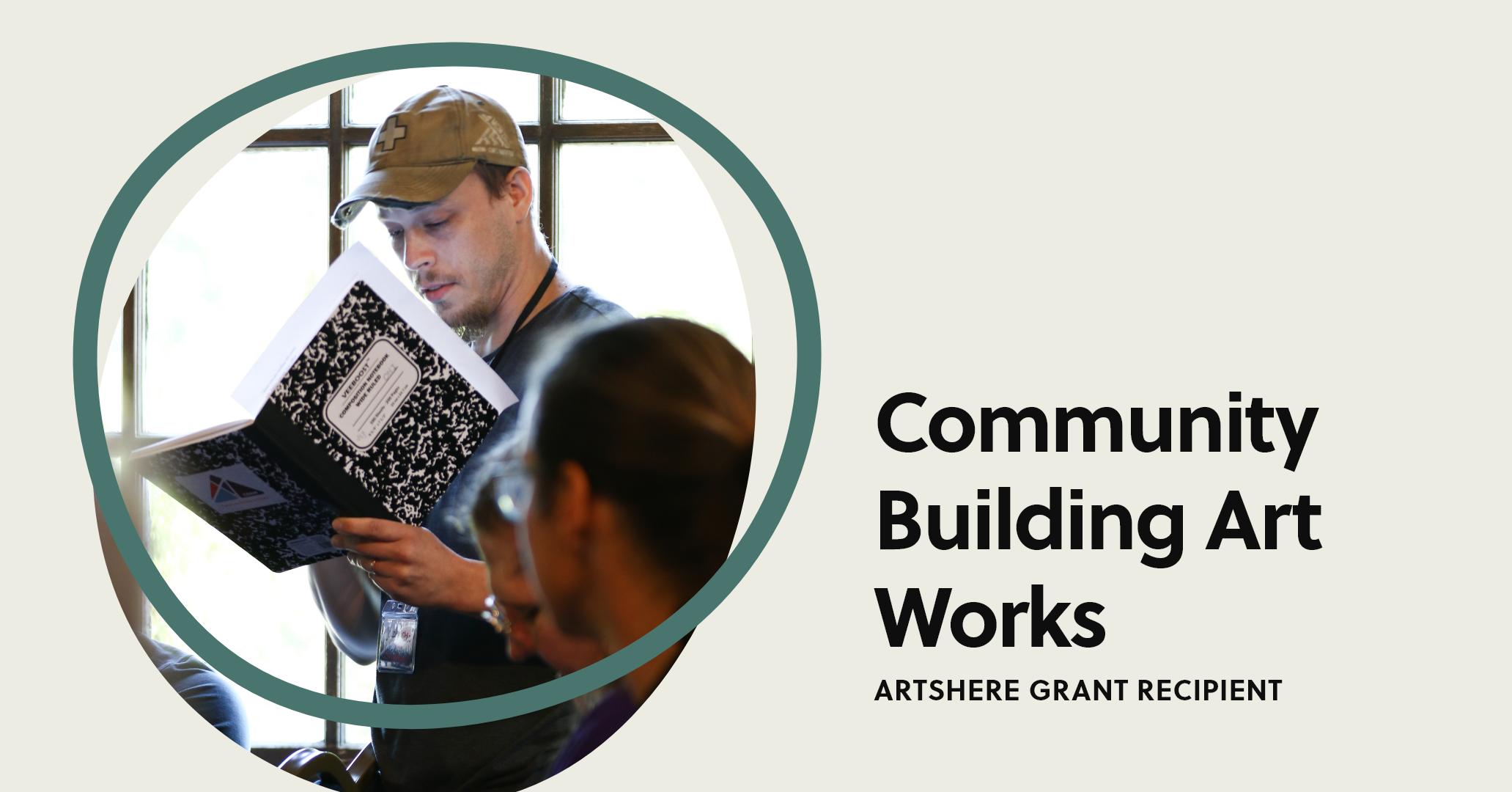 A beige background with a photo of Image displays a man in a baseball cap reading from a notebook while standing, encircled by a green ArtsHERE logo. Black text reads, “Community Building Art Works: ArtsHERE Grant Recipient.”<br />
