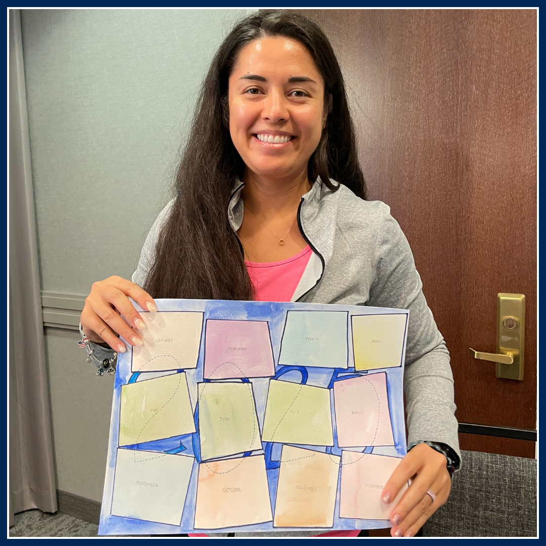 A caregiver holding a piece of artwork they created, smiling proudly. The collaged artwork appears colorful and detailed, showcasing their creativity and talent.