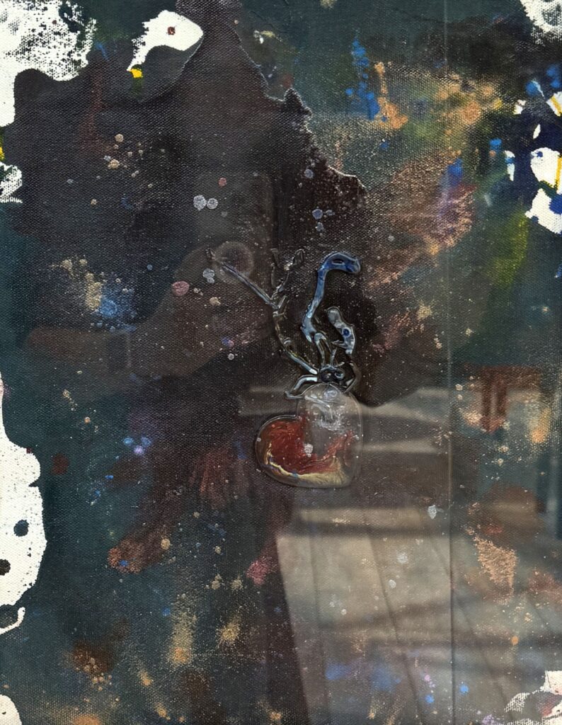 Lifeline (2019) — Mixed Media, 12"×14" — Belena Stuart Marquez Abstract mixed‑media painting with a dark background scattered with speckles and splashes of white, blue, yellow, and reddish‑brown. At the center is a small, glossy, three‑dimensional heart shape attached to a branching form that extends upward. A small “BSM” signature appears in the lower right corner.