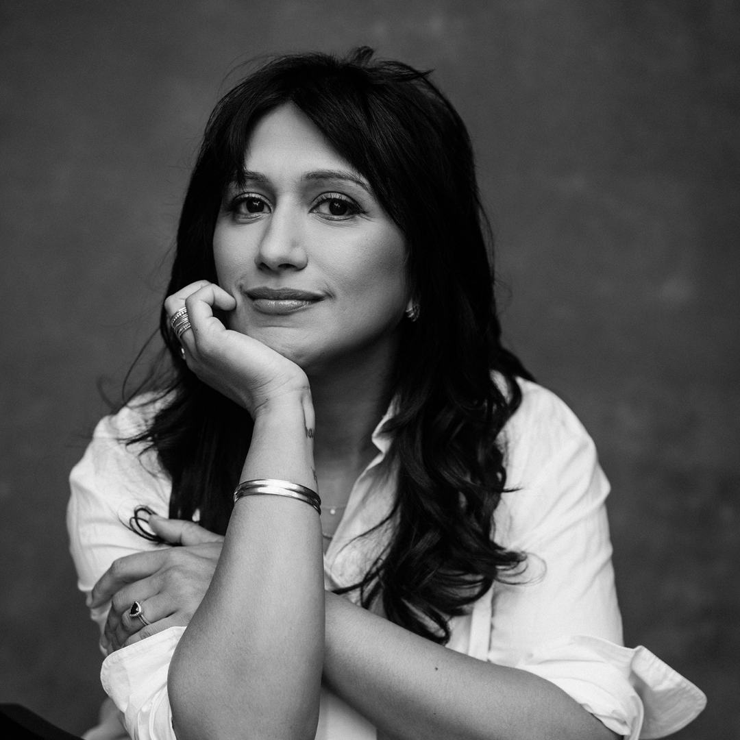 Black and white headshot of Seema Reza resting her head on her hand