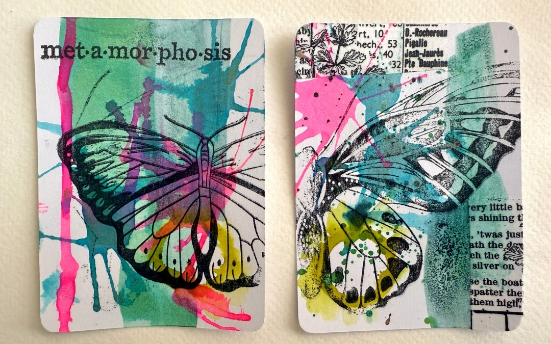 Artist Trading Cards — Visual Arts Workshop Two mixed‑media artist trading cards feature vibrant watercolor splashes in green, pink, blue, and yellow with black ink butterfly outlines layered on top. One card includes the printed word “met·a·mor·pho·sis,” and the other incorporates botanical illustrations and text fragments, creating a collage effect.