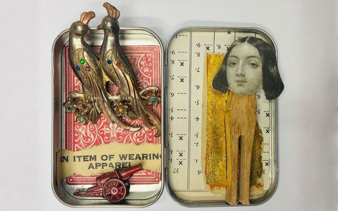 Tiny Tin Worlds — Artwork by Robin Roberts Two small tin containers display mixed‑media assemblage art created by Robin Roberts: one with patterned red paper, jeweled bird figures, a tiny cannon, and a paper strip reading “An Item of Wearing Apparel,” and the other with a clothespin figure topped with a vintage portrait cutout, gold foil, and numerical markings.
